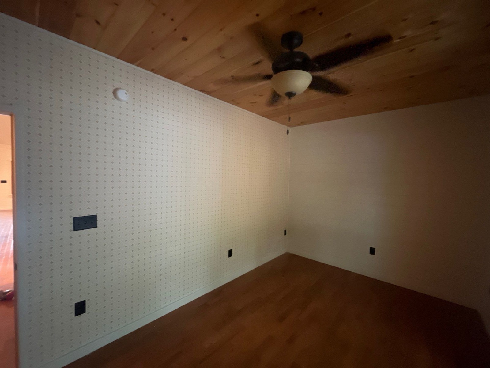 Two bedroom walls hung with small-print wallpaper in a North Georgia cabin