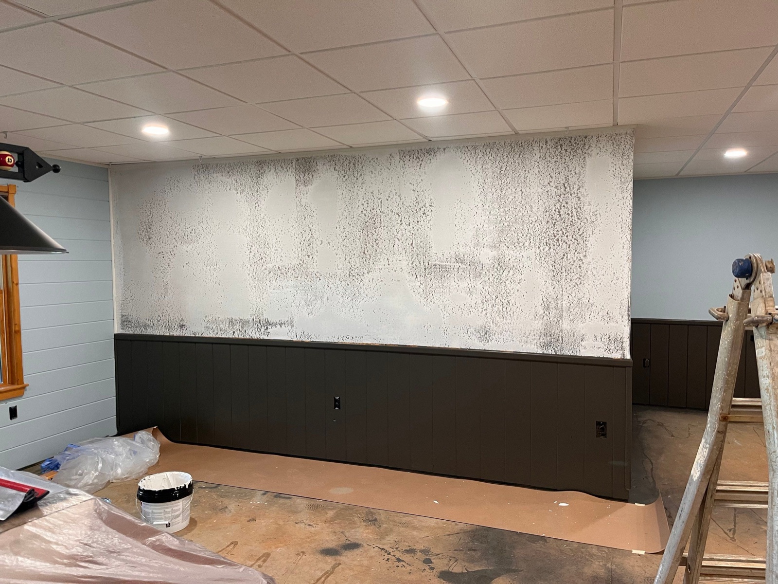 Wall masked, floors covered, and primer going on during an interior painting job at a North Georgia cabin